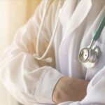 Doktor önlüğüyle hastanede, mikrofon başında radyoda